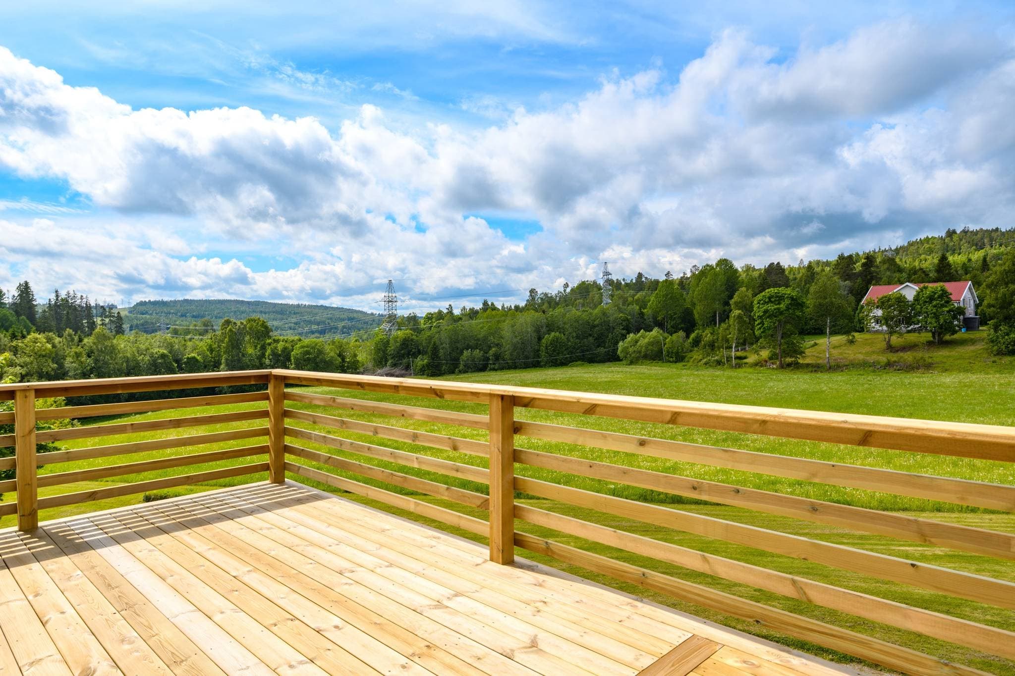Vy från balkong över åker, skog, berg och övre bostadshus.