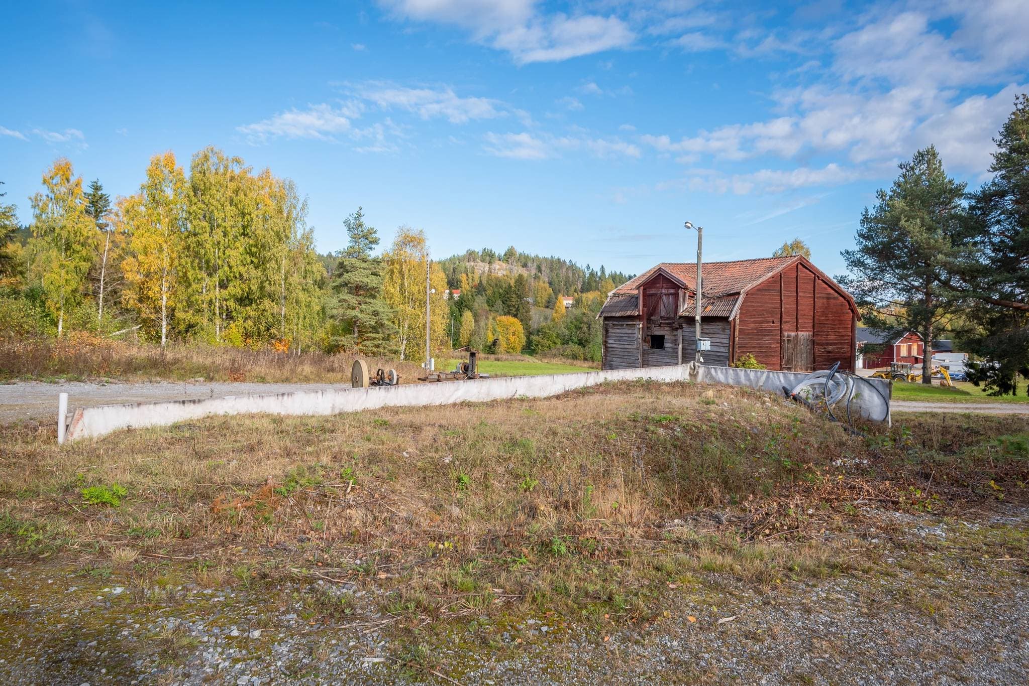 Förberedd byggnadsgrund – ca 100 m² På gården finns en förberedd byggnadsgrund om cirka 100 m², med stora möjligheter för framtida utveckling. Här finns förutsättningar att uppföra exempelvis ett garage, en maskinhall, ett stall eller annan ekonomibyggnad, helt utifrån framtida behov och önskemål. Grunden är förberedd med kulvertrör för värme samt ledning för dricksvatten från det övre bostadshuset. Det innebär att en framtida byggnad kan anslutas till den befintliga bergvärmeanläggningen och värmas upp på ett energieffektivt sätt. För den som önskar finns även möjlighet att installera ett separat pannrum och ansluta detta till den befintliga kulverten. En vedpanna med hög kapacitet ingår och ger möjlighet att värma både den nya byggnaden och det övre bostadshuset med ved. Till projektet finns dessutom färdiga väggsektioner samt inköpta armeringsnät och armeringsjärn för den fortsatta byggnationen. En betydande del av markarbetet och byggförberedelserna är redan utförd, vilket ger goda förutsättningar för den som vill färdigställa byggnaden efter egna behov.